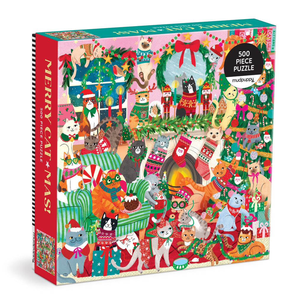 The Merry Catmas! 500 Piece Family Puzzle by Rebecca Jones showcases cats in Christmas outfits in a festive living room with decorations, stockings, gifts, and a glowing fireplace.