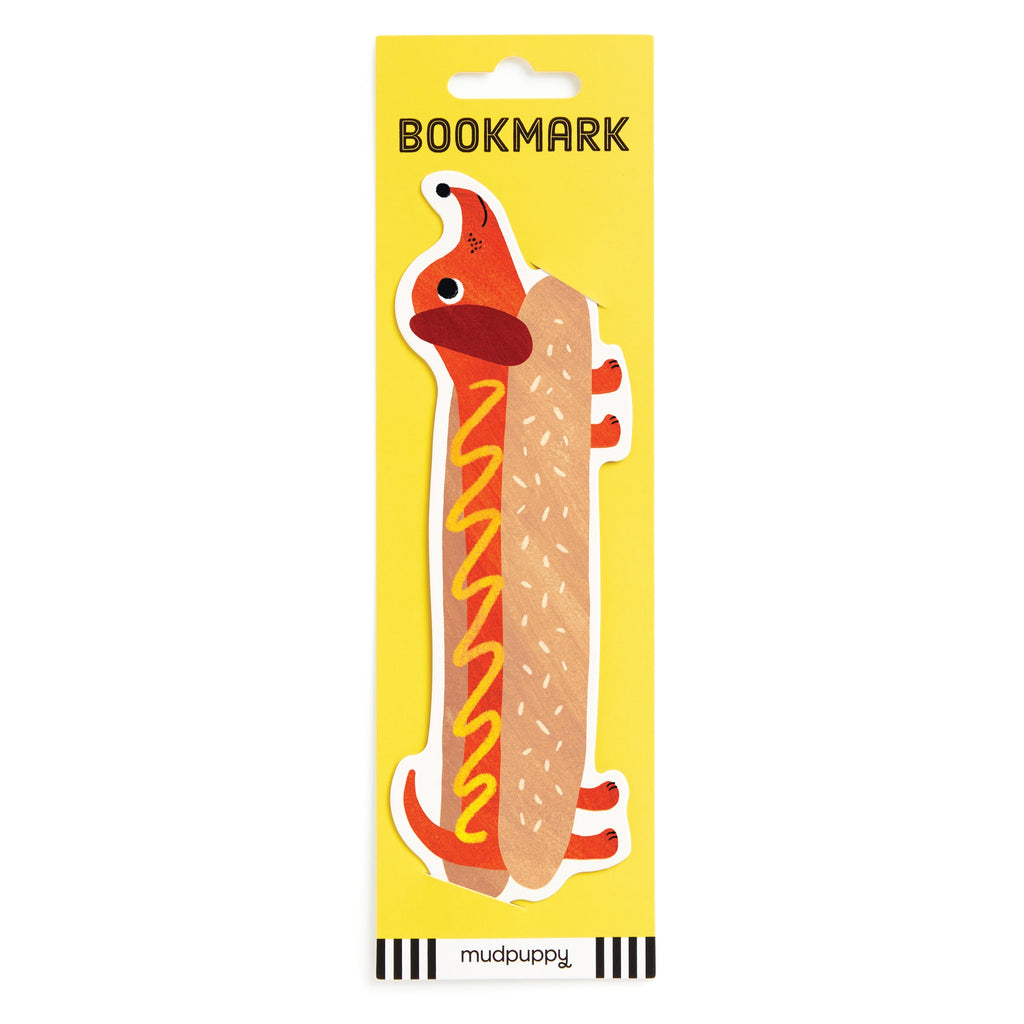 Keep your place in style with the Hot Dog Bookmark by Rebecca Jones, shaped like a dachshund dressed as a mustard-topped hot dog. It comes packaged with yellow BOOKMARK labeling and features the brand name at the bottom.