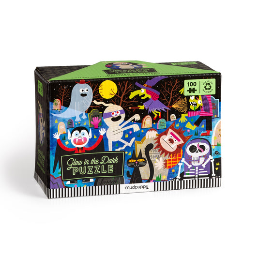 A brightly colored box for the Rob Hodgson Haunted Graveyard 100 Piece Glow in the Dark Puzzle, featuring cartoon ghosts, witches, skeletons, and vampires in a spooky night scene—bringing Halloween fun to life!.