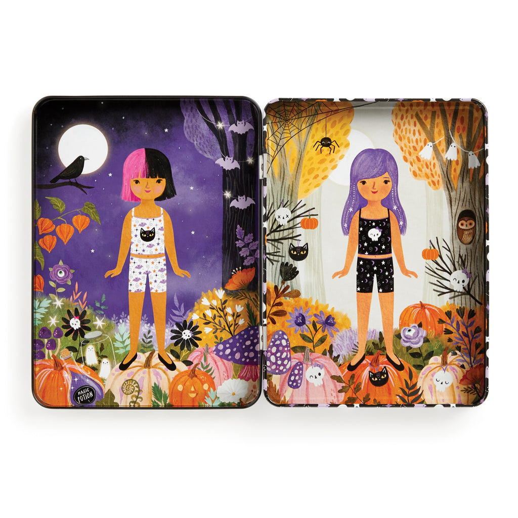 The Spooky Season Magnetic Dress-up Play Set by Jenny Miriam Hughes includes two illustrated tins with girls in pajamas, set in whimsical autumn scenes—one at night and one by day—featuring pumpkins, cats, mushrooms, and owls for imaginative play.