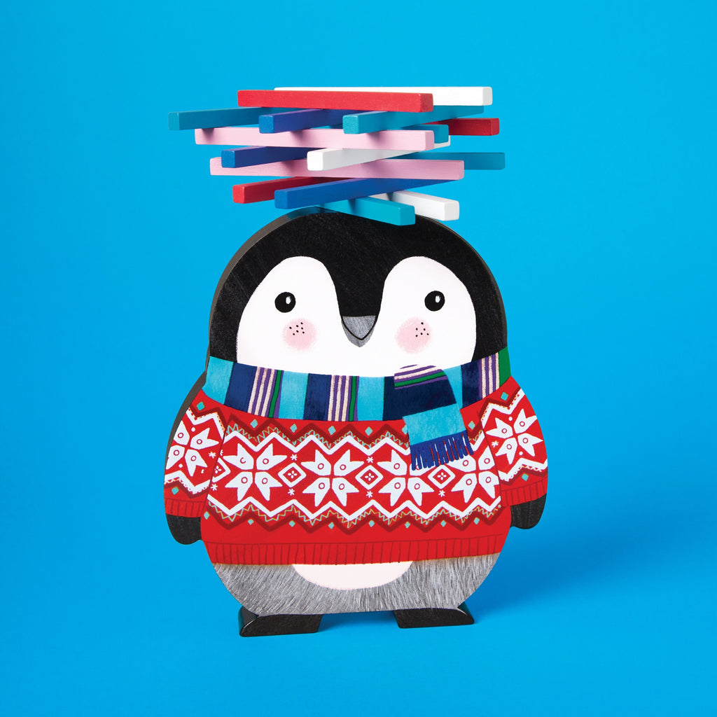 The Rebecca Jones Penguin Stack-up Wooden Balancing Game features a cute cartoon penguin in a red and white sweater with a blue scarf, balancing colorful blocks on its head for fun fine motor skill development.