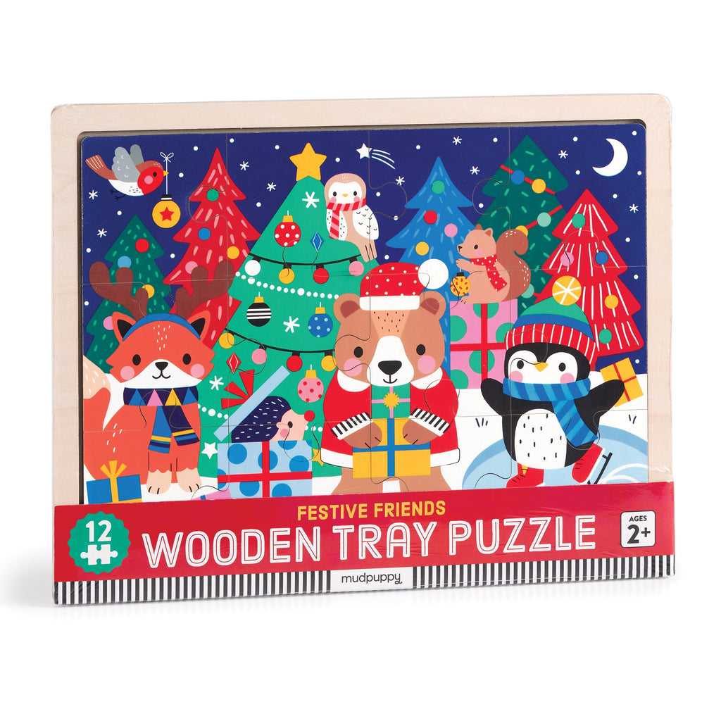 The Wendy Kendall Festive Friends 12 Piece Wooden Tray Puzzle features holiday animals in winter clothes by Christmas trees under a starry sky. Box reads Festive Friends Wooden Tray Puzzle.
